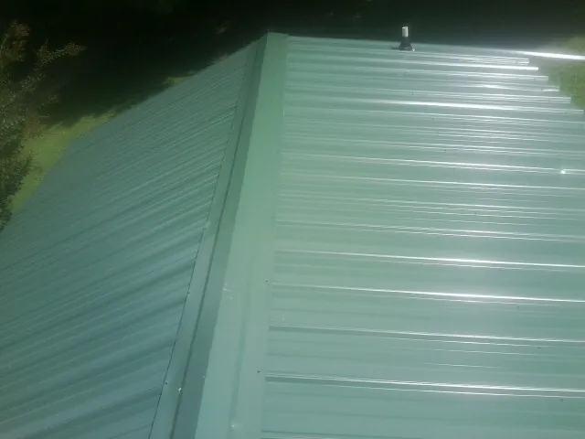 New green metal panels meeting at the ridge of a roof — Flat Roof Repair work by our crew in Panorama City