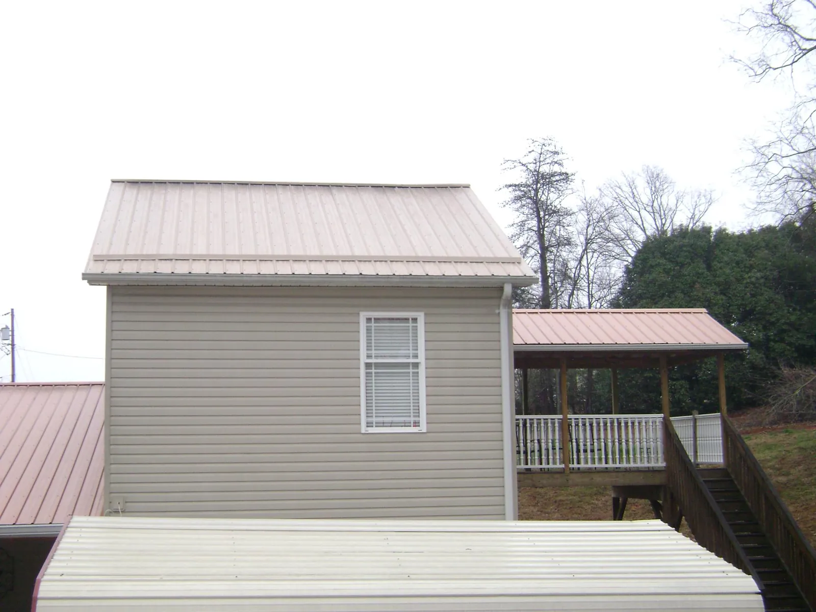 Tan metal roofs on a two story addition and attached porch, from a Roof Replacement job in Panorama City