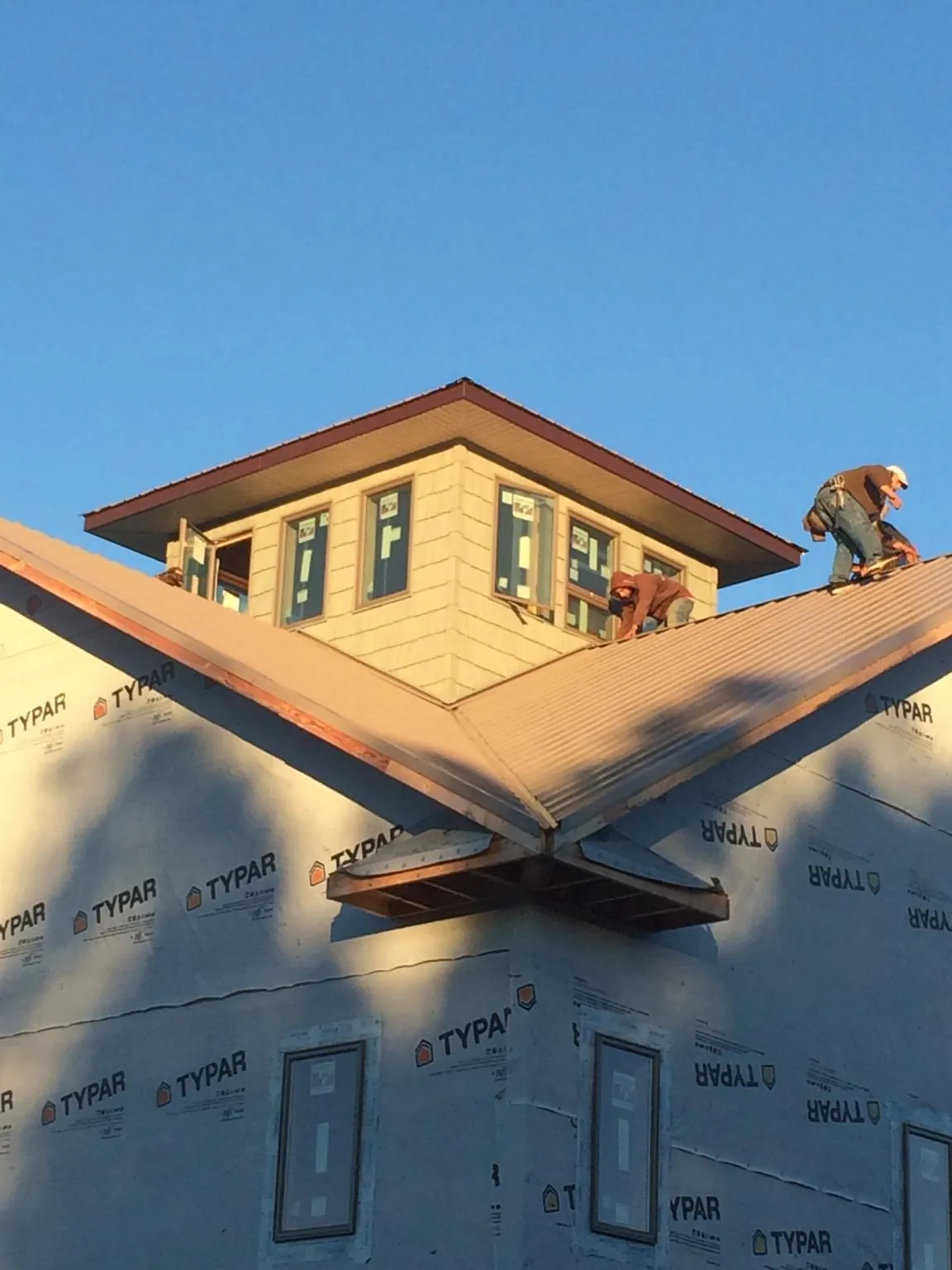 Roofers working around a rooftop cupola on a new metal roof at sunset — Roof Waterproofing in Panorama City by Roofing Brothers